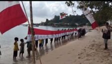 Masyarakat bersama generasi muda Desa Gemia membentangkan bendera Merah Putih raksasa sepanjang 45 meter di pesisir pantai. || dok : Kasedata