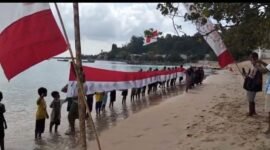 Masyarakat bersama generasi muda Desa Gemia membentangkan bendera Merah Putih raksasa sepanjang 45 meter di pesisir pantai. || dok : Kasedata