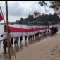 Masyarakat bersama generasi muda Desa Gemia membentangkan bendera Merah Putih raksasa sepanjang 45 meter di pesisir pantai. || dok : Kasedata