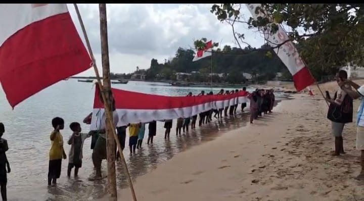 Masyarakat bersama generasi muda Desa Gemia membentangkan bendera Merah Putih raksasa sepanjang 45 meter di pesisir pantai. || dok : Kasedata